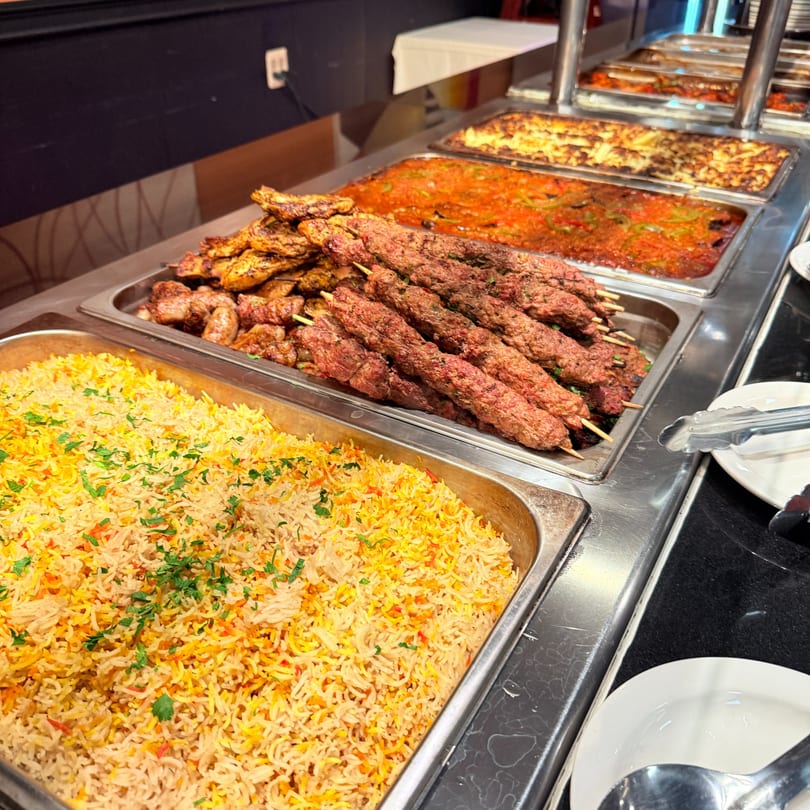 A buffet line with trays of middle-eastern rice, kebabs, and other dishes at Marib Restaurant.